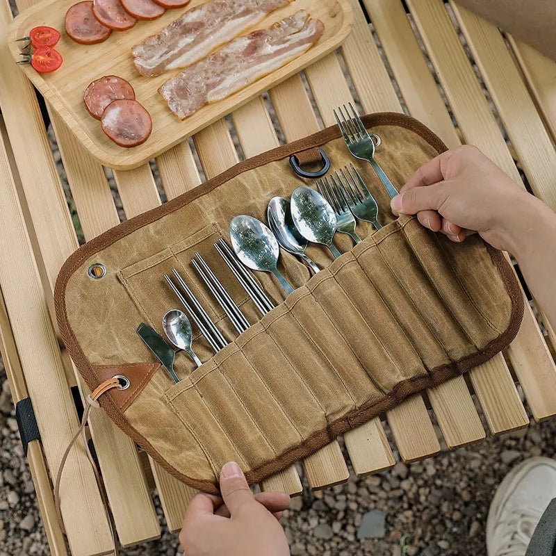 Green waxed canvas storage bag containing a wooden handle cutlery set for outdoor use.