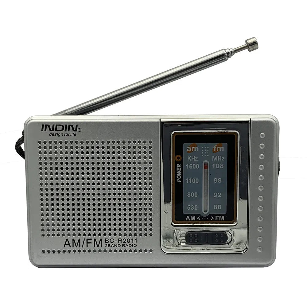 Portable silver grey FM AM radio on table, compact ABS body with built-in speaker and dial controls