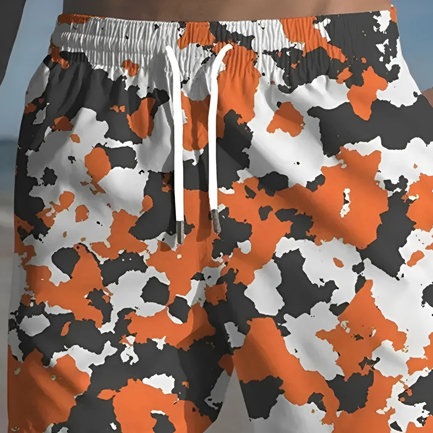 Colourful printed men's beach shorts with an elastic waistband on a neutral background.