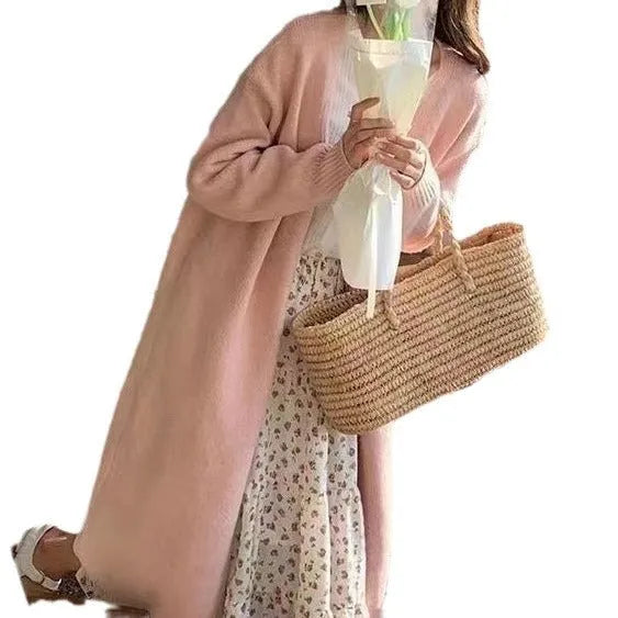 A woman wearing a khaki-colour, loose-fit knitted cardigan with a V-neck and long sleeves.