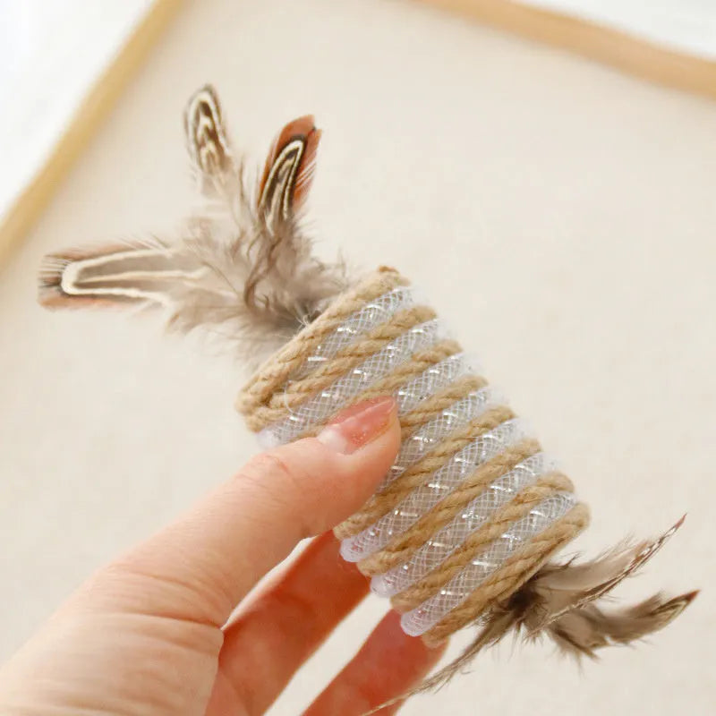 Beige cat toy with hemp rope texture, feathers, and a bell on a wooden roller for scratching and play.