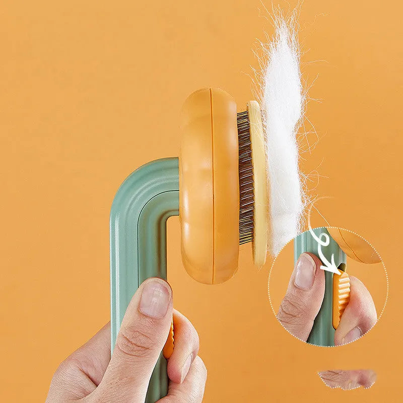Pumpkin-coloured self-cleaning pet grooming brush with stainless steel needles for cats and dogs.