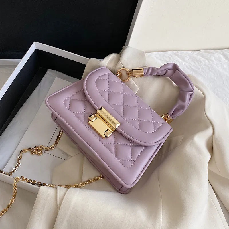 Purple trapezoidal square messenger bag with long crossbody strap shown alongside black and beige colour options