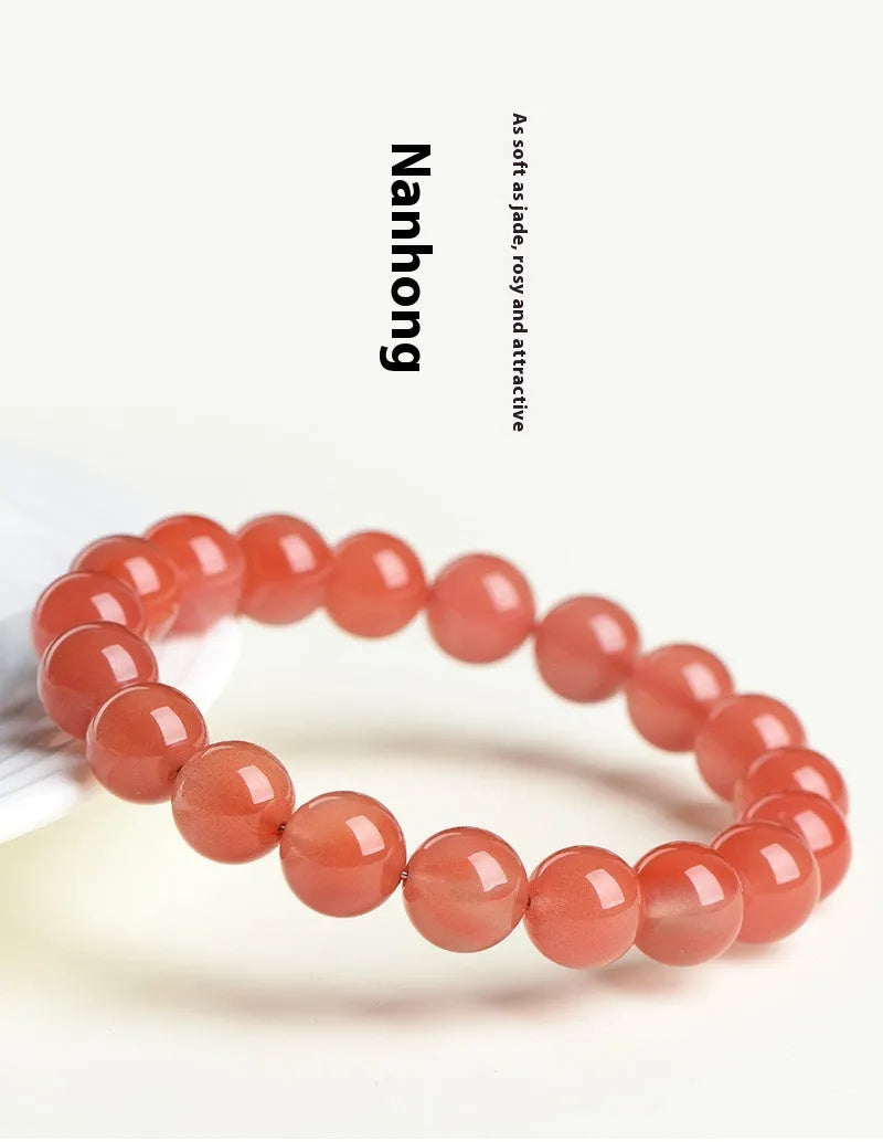 Natural cherry red agate beaded bracelet with adjustable metal clasp on a wrist, showing scattered polished stones.