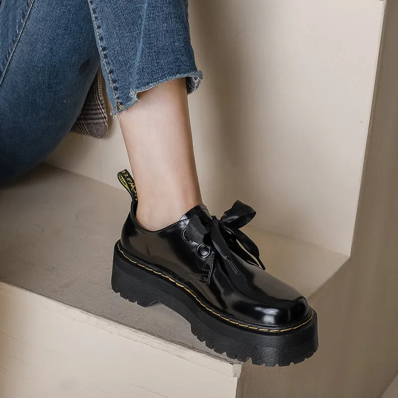 White and black women's thick soled shoes with ribbon and cross straps and laced closure.