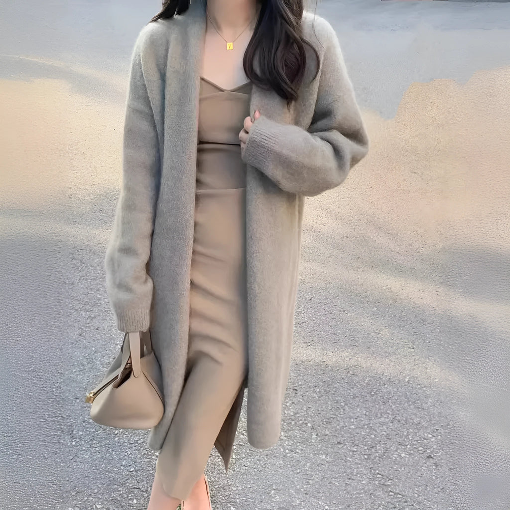 A woman wearing a khaki-colour, loose-fit knitted cardigan with a V-neck and long sleeves.