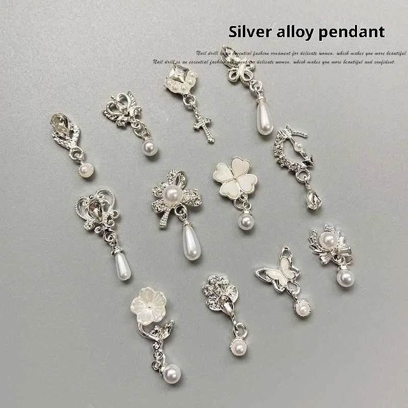 Silver nail art pendant charms with pearl and tassel details, assorted pack on black background