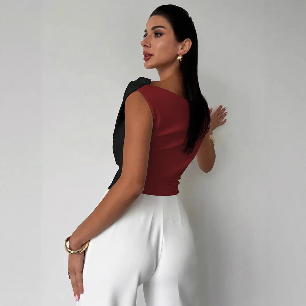 Color-blocked women's top with asymmetric shoulder and ruffled hem, slim fit, black with white panels, polyester fabric.