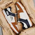 Pair of plain white and blue lace-up casual sneakers on a neutral background.