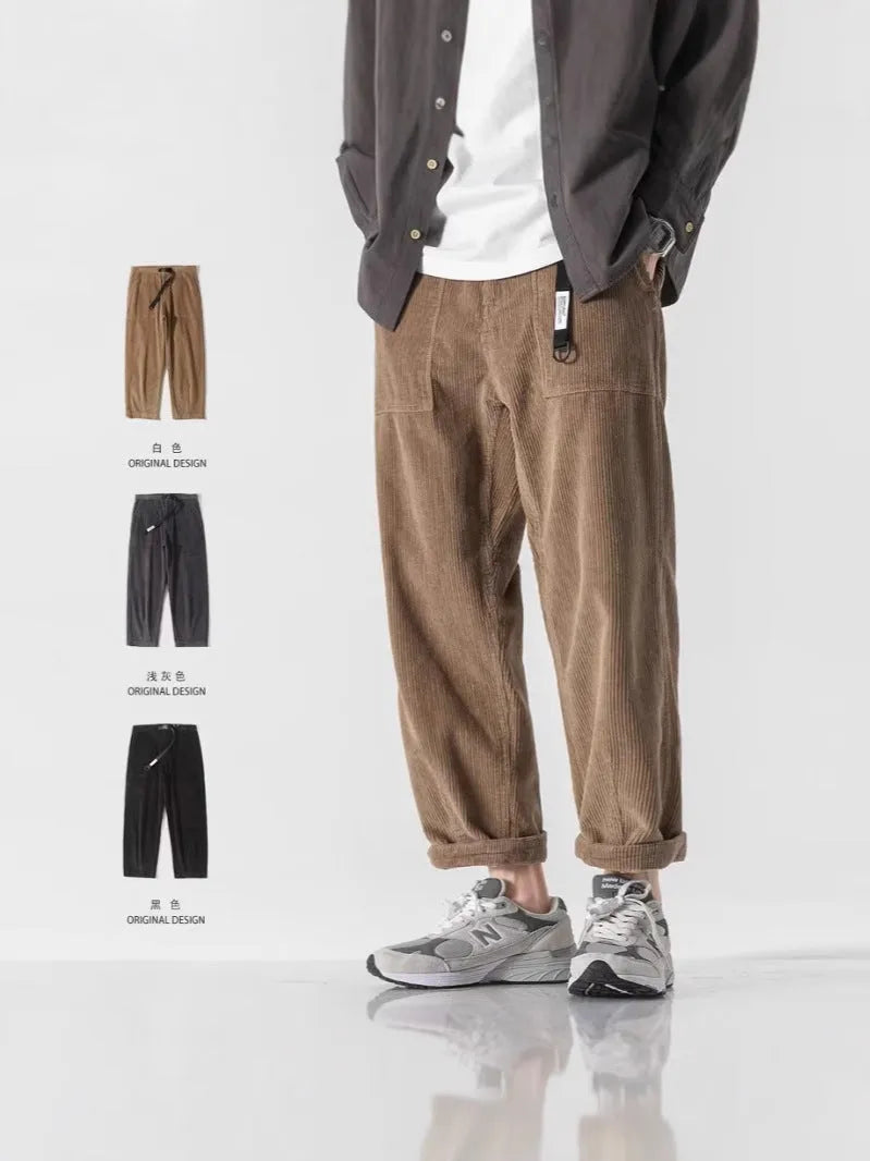 Man wearing loose straight leg casual trousers in dark grey, showing tapered fit and wide leg opening.