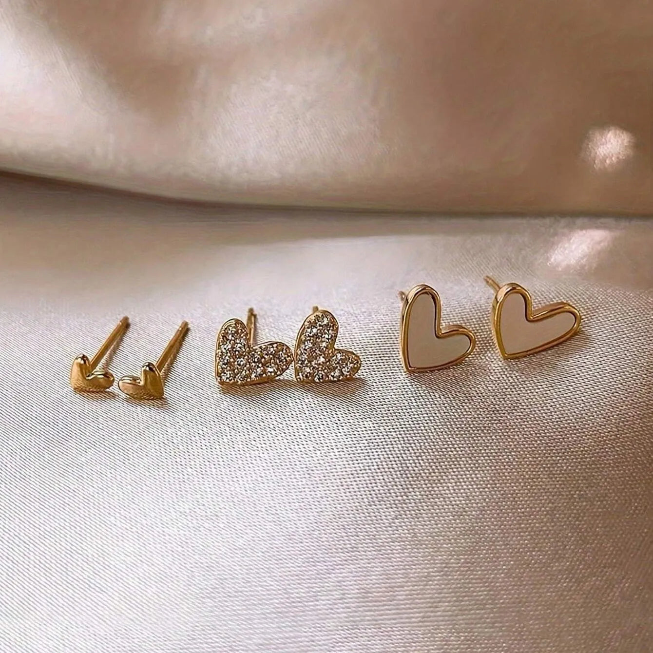 Set of three pairs of heart-shaped alloy earrings in gold, black, black and white, or pink colours