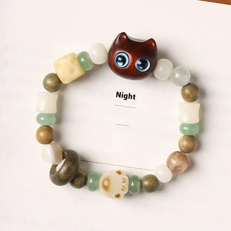Beaded bracelet with a cube sugar cat's paw charm in guajacwood or ebony, featuring jade beads and a choice of yellow or blue eyes.