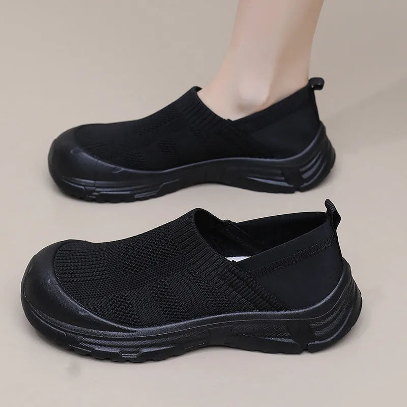 Women's black slip-on shoe with a cloth upper and soft PVC sole on a white background