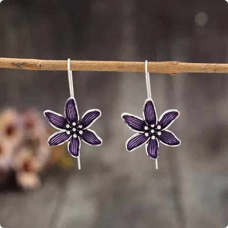 A pair of purple flower-shaped alloy earrings with an electroplated finish on a white background.