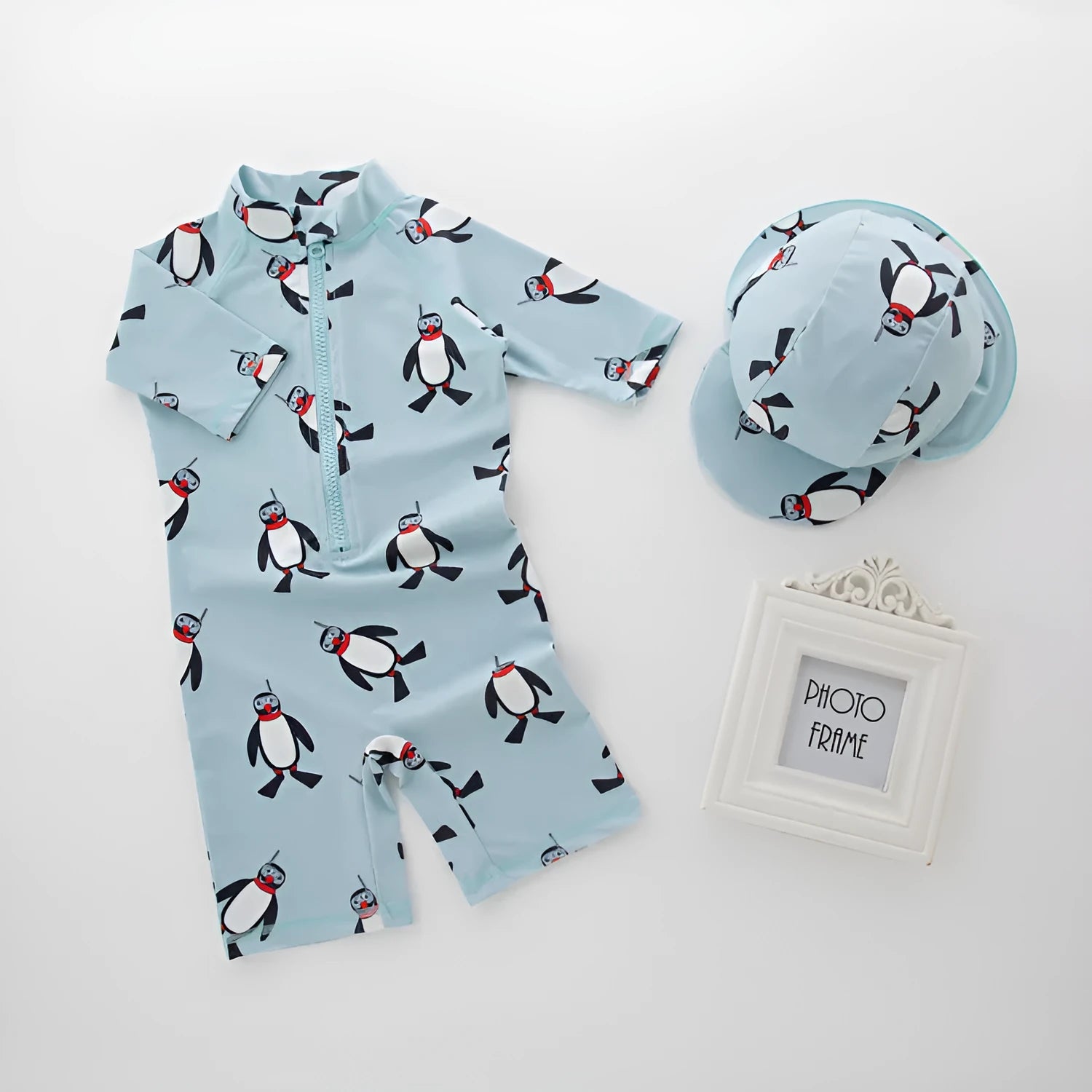 Boy's penguin print long sleeve swim shirt and matching cap set for sun protection.