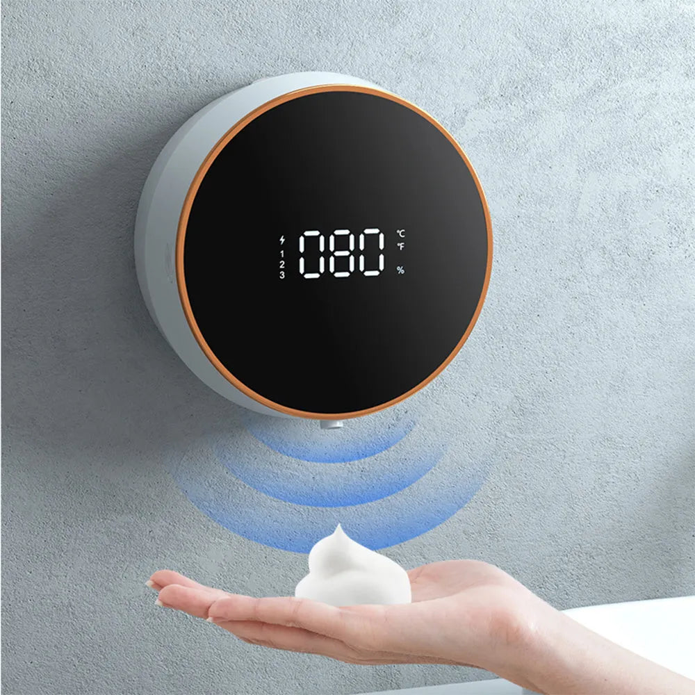 Black smart automatic foam dispenser mounted on a wall with hands activating the sensor.