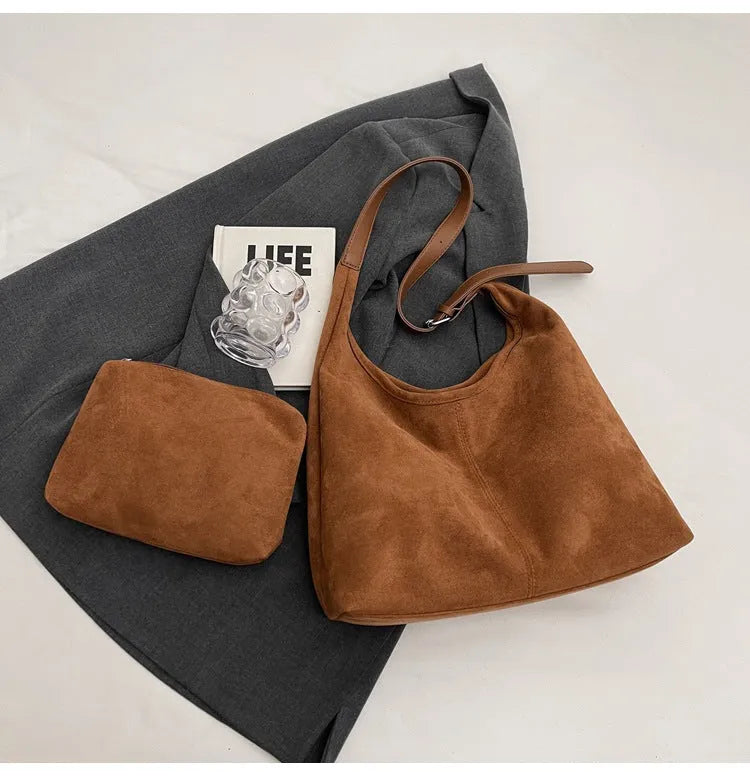 Women's suede bucket bag in black with stitching detail, single shoulder strap, and outer sandwich pocket