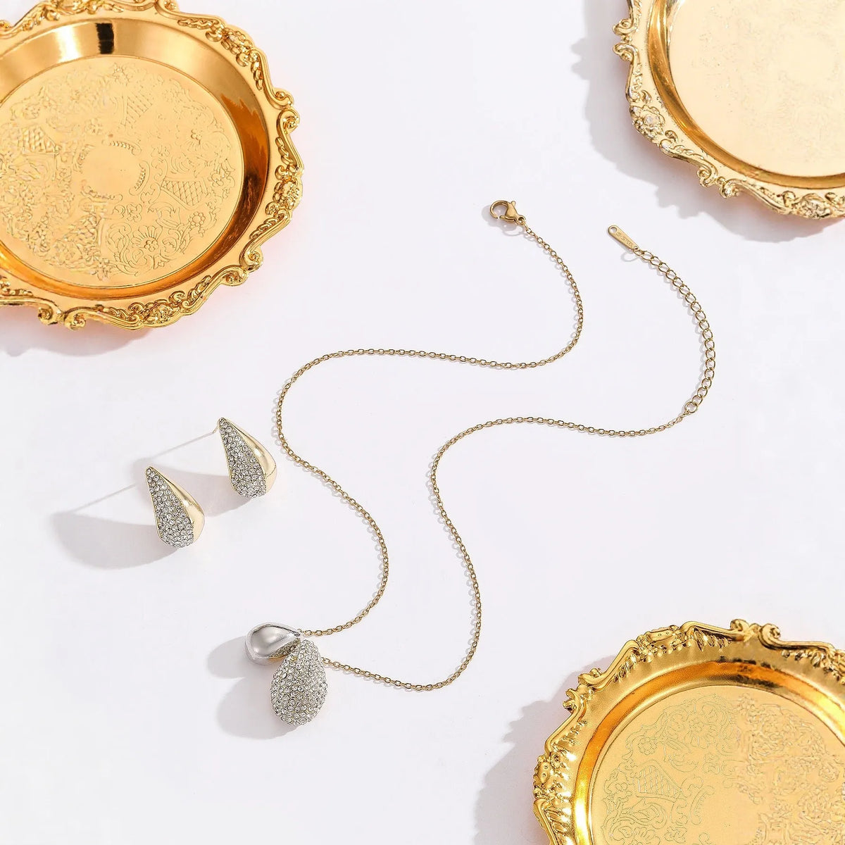 Elliptical necklace and earring set with full diamond droplet shape, silver-tone finish
