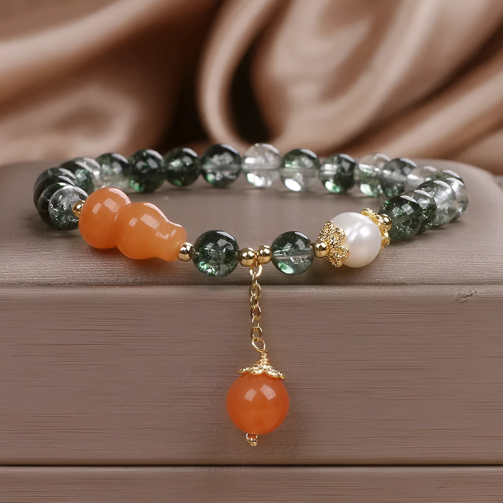 Green phantom quartz crystal bracelet with pearl and rhinestone accents on women's wrist