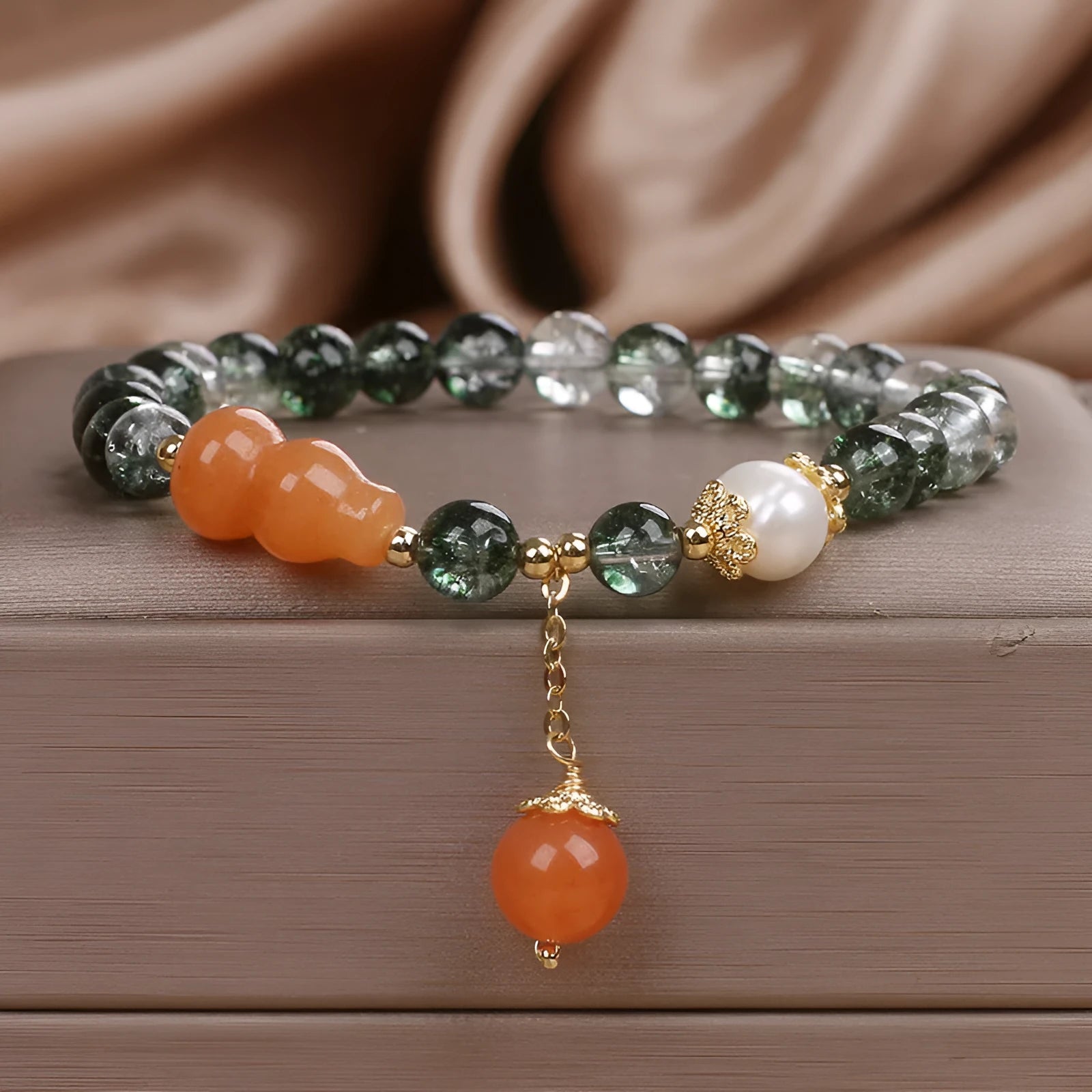 Green phantom quartz crystal bracelet with pearl and rhinestone accents on women's wrist