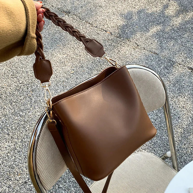 Retro khaki woven crossbody bucket bag with adjustable strap shown worn on shoulder