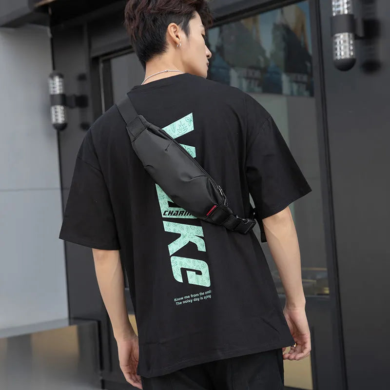 Black oxford cloth men's crossbody waist pack showing front zipper and strap.