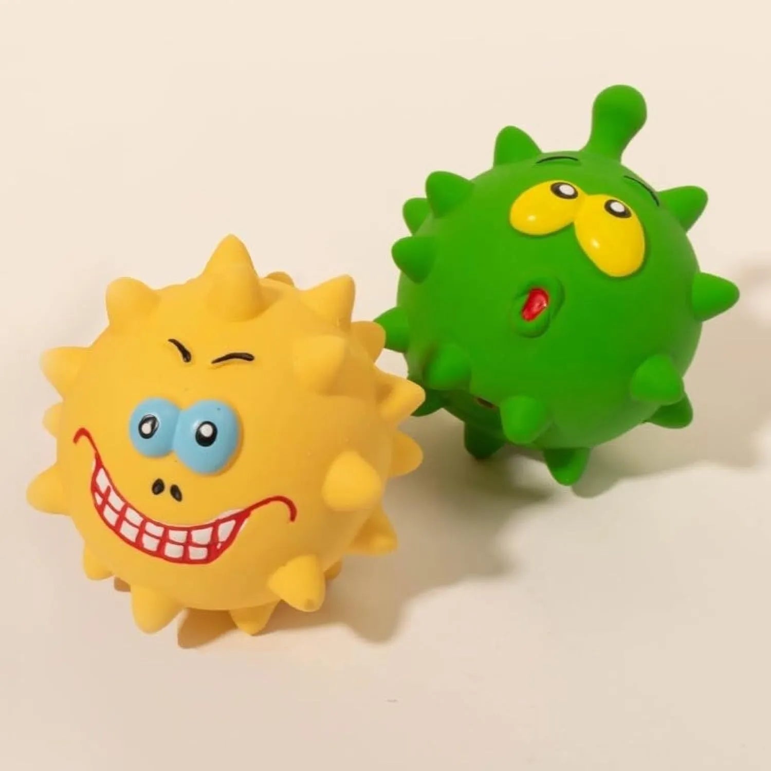 Set of four colourful latex squeaky dog balls with cute faces, shown next to a dog.