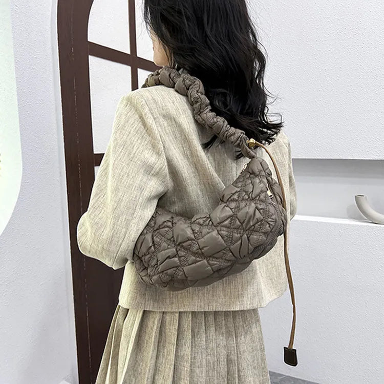 Women's light beige nylon cloud underarm messenger bag with a long adjustable shoulder strap.