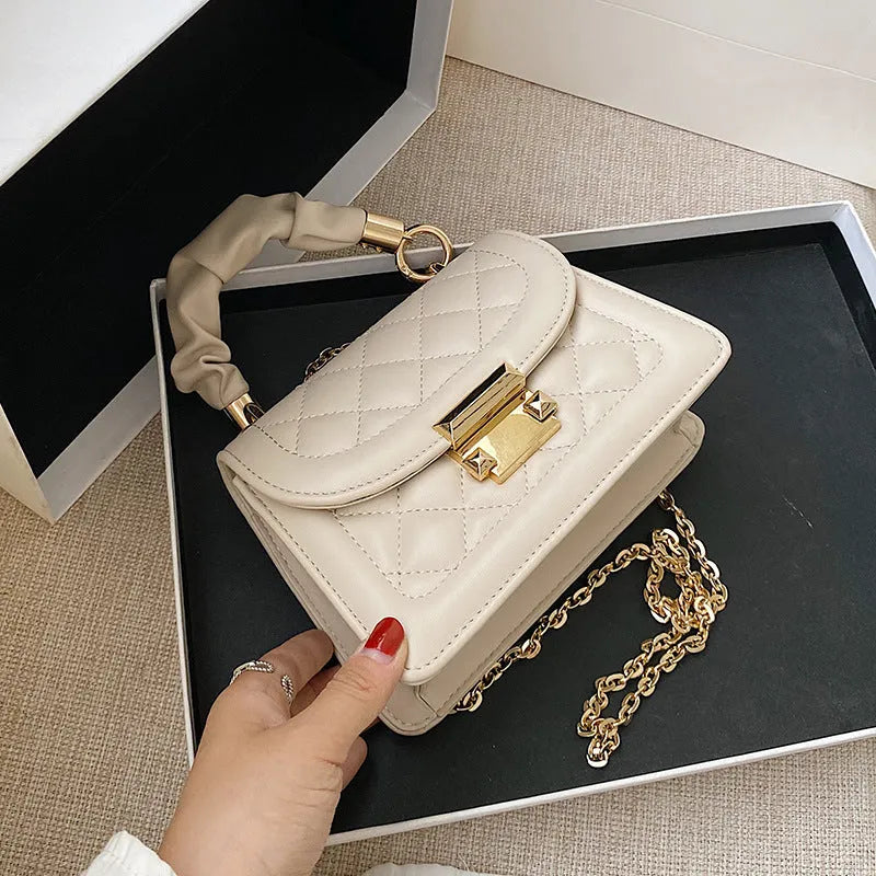 Purple trapezoidal square messenger bag with long crossbody strap shown alongside black and beige colour options