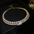 Silver geometric curved open necklace on a clavicle-length chain, resting on a collarbone.