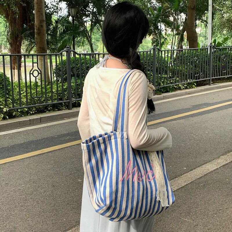 Blue striped letters printed on a pink, blue, and white striped cotton canvas bag for daily matching.