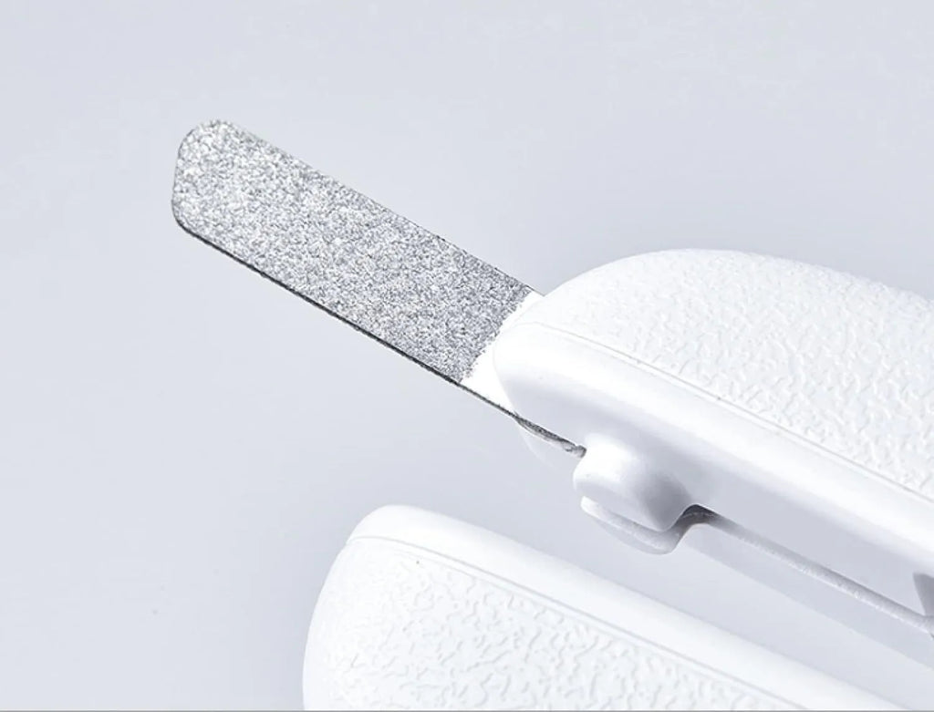 White pet nail clippers with LED light and transparent guard, shown with a separate nail file on a table.
