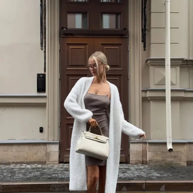 Long white knitted cardigan jacket on a hanger, showing extended length and loose fit.