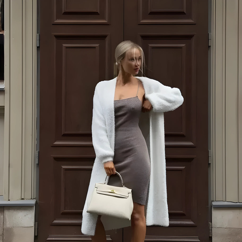Long white knitted cardigan jacket on a hanger, showing extended length and loose fit.