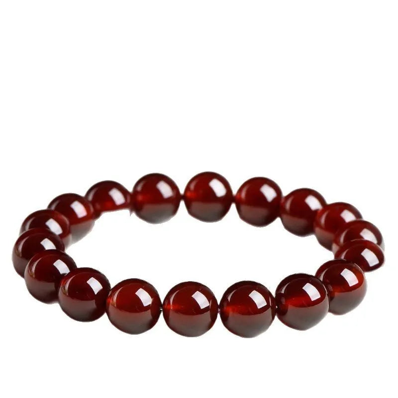 Natural Orange Red Garnet ball bead bracelet with a metal Ruyi charm on a white background.
