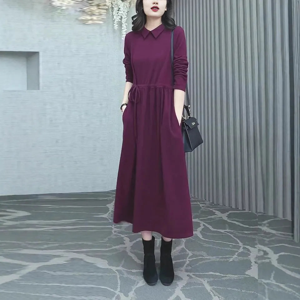 A purplish-red plus size winter dress with long sleeves and a long, flowing skirt, laid flat.