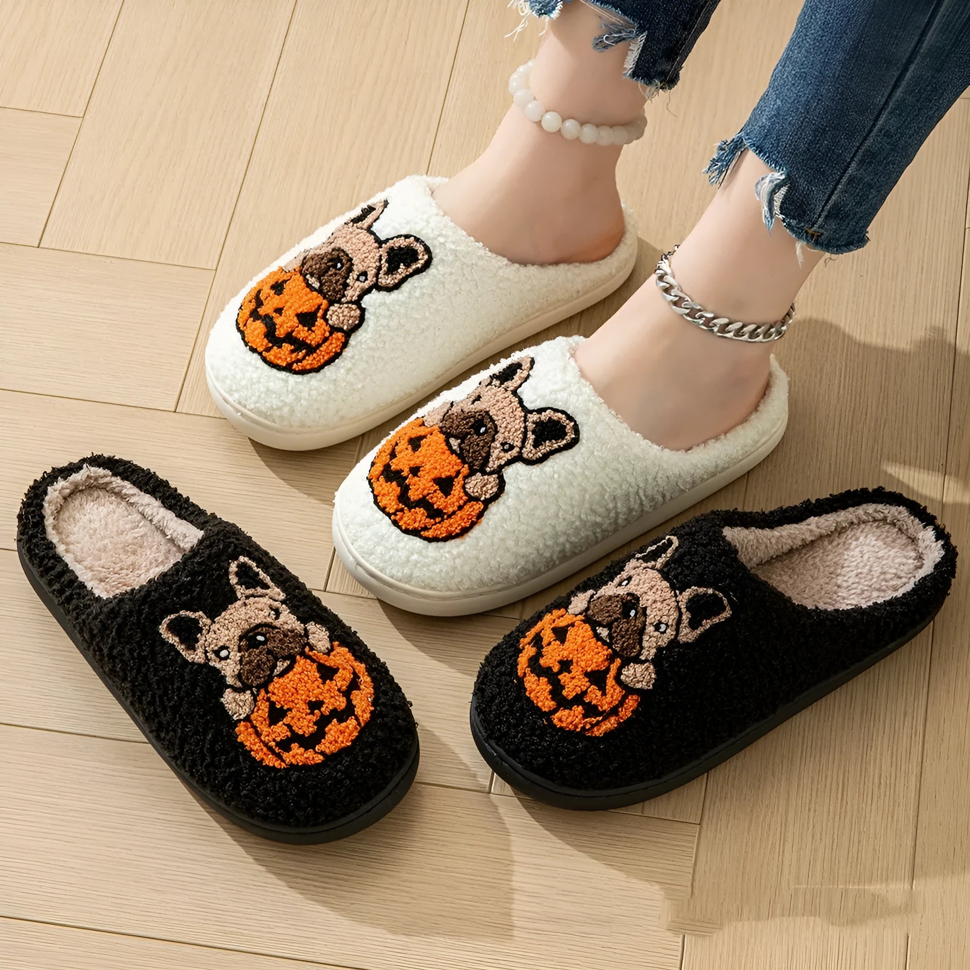 Black plush Halloween slippers with pumpkin print and a thick, textured TPR rubber sole.