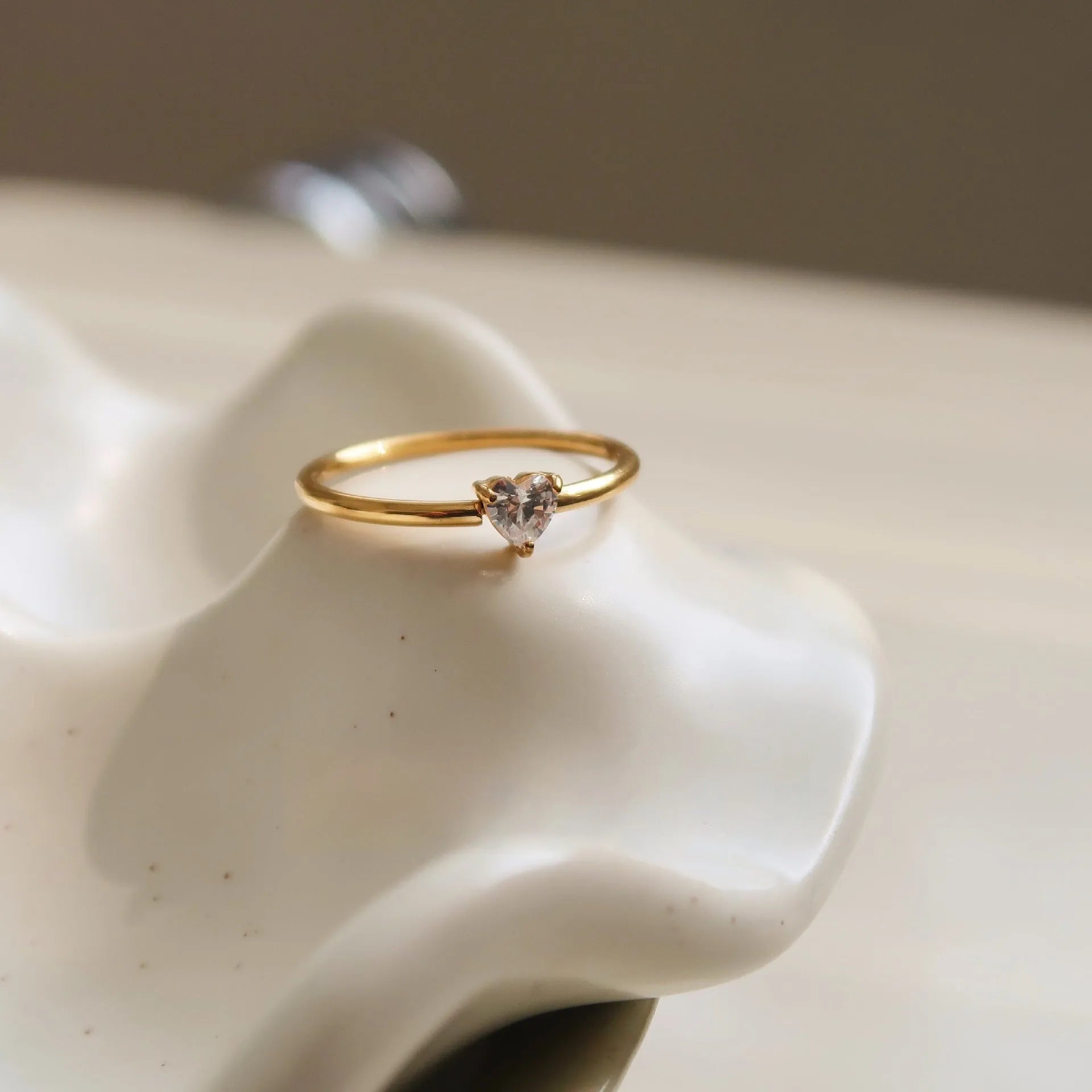 Gold heart-shaped ring and gold oval ring on display, both in stainless steel for women.