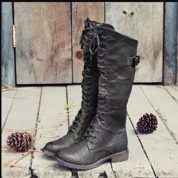 Black chunky heel high leg boot on a white background, showing round toe and low heel.