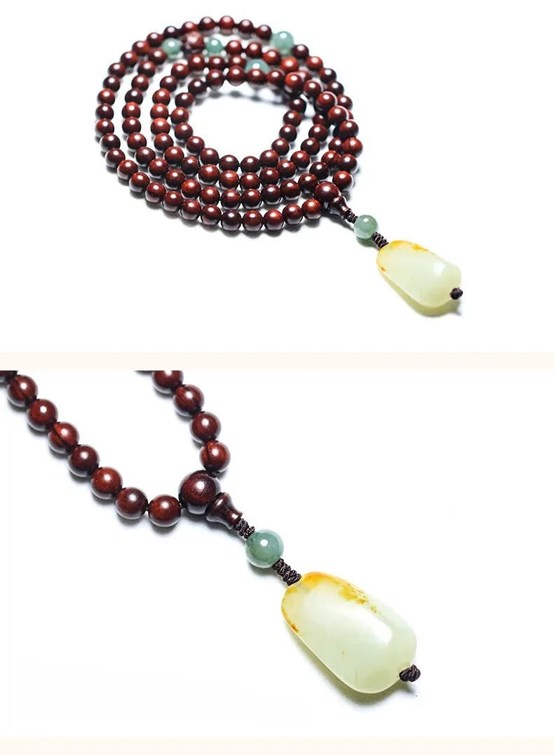 Close-up of a hand-carved rosewood beaded bracelet with 108 6mm beads and a carved Hotian jade pendant.
