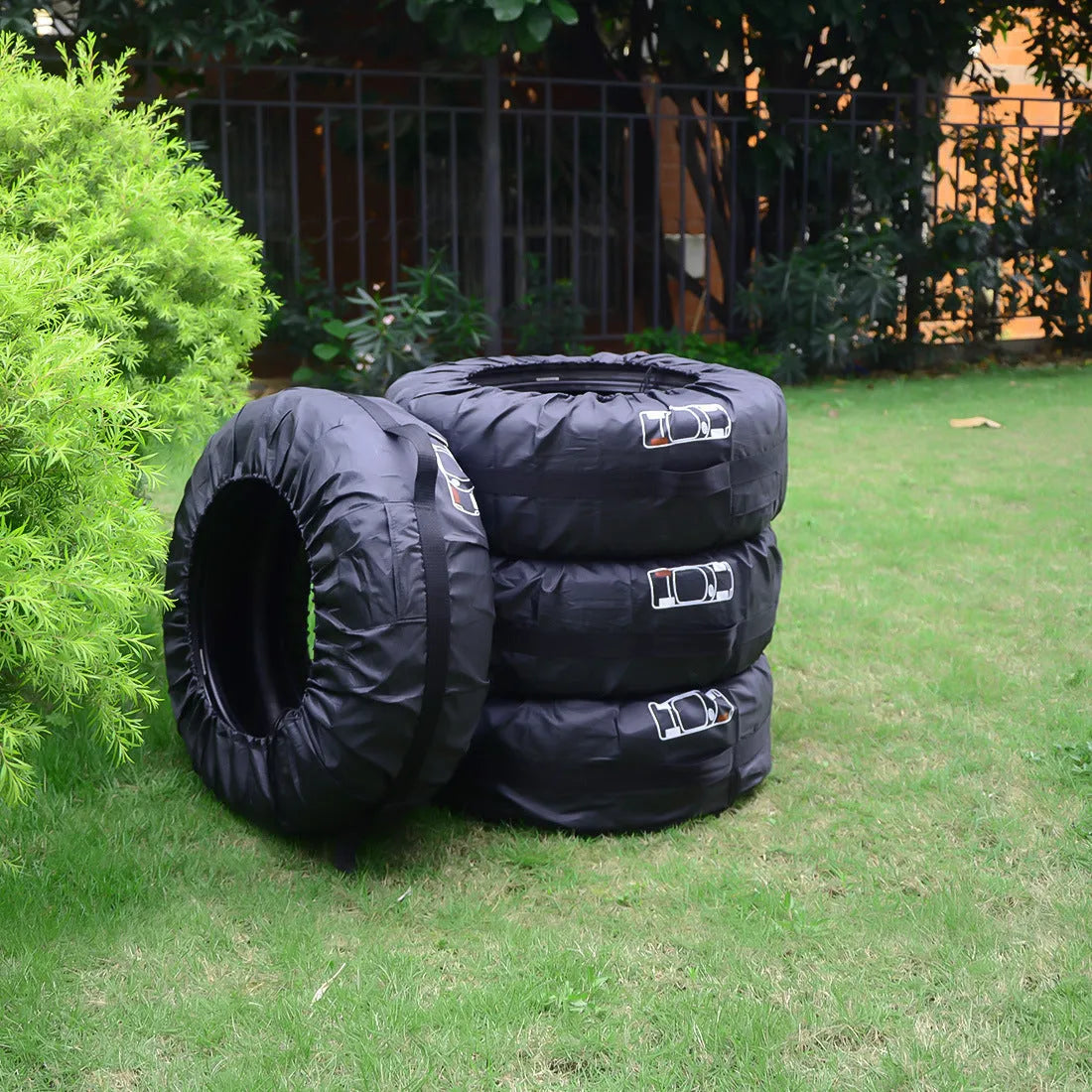 Set of four black Oxford cloth car tyre protective covers laid flat, showing their circular shape and durable fabric texture.