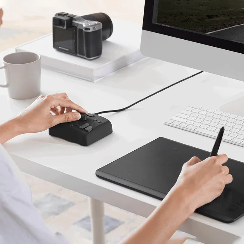 TourBox NEO black auxiliary keyboard controller for video editing on a desk.