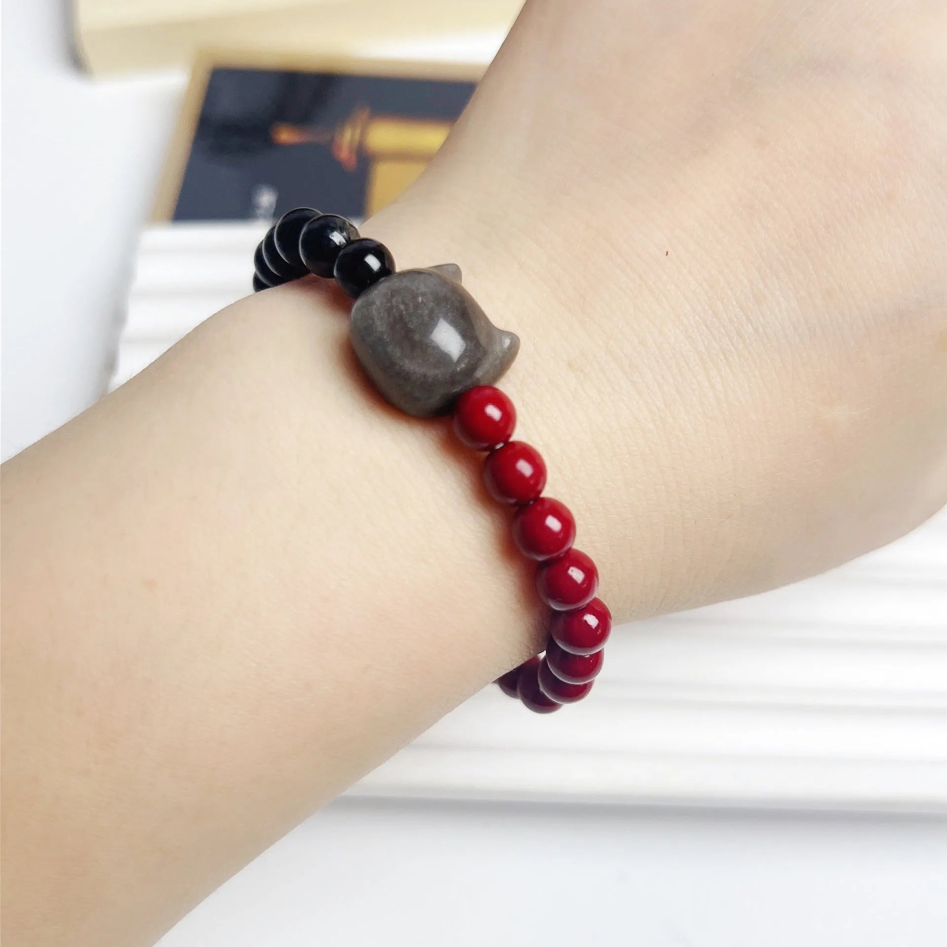 Obsidian-coloured cat charm on a colourful elastic bracelet strap.