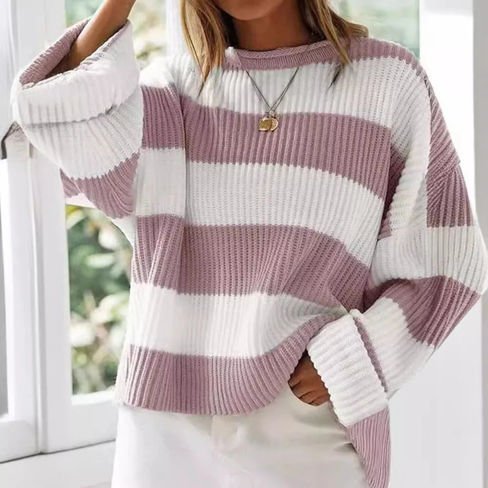 Woman wearing a loose striped sweater with long bell sleeves and white crocheted flower details on the front.