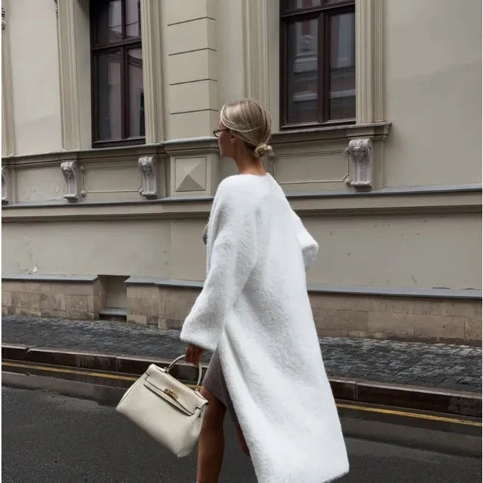 Long white knitted cardigan jacket on a hanger, showing extended length and loose fit.