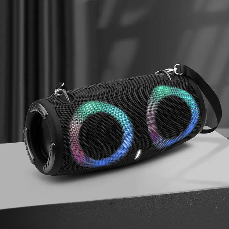 War Drum portable Bluetooth speaker with glowing RGB light ring in camouflage colour, sitting on grass.