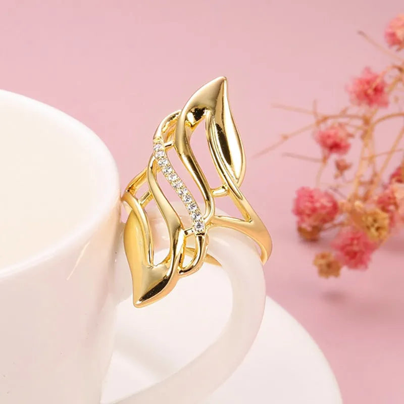 Gold coloured women's ring with an exaggerated curved design on a copper band.