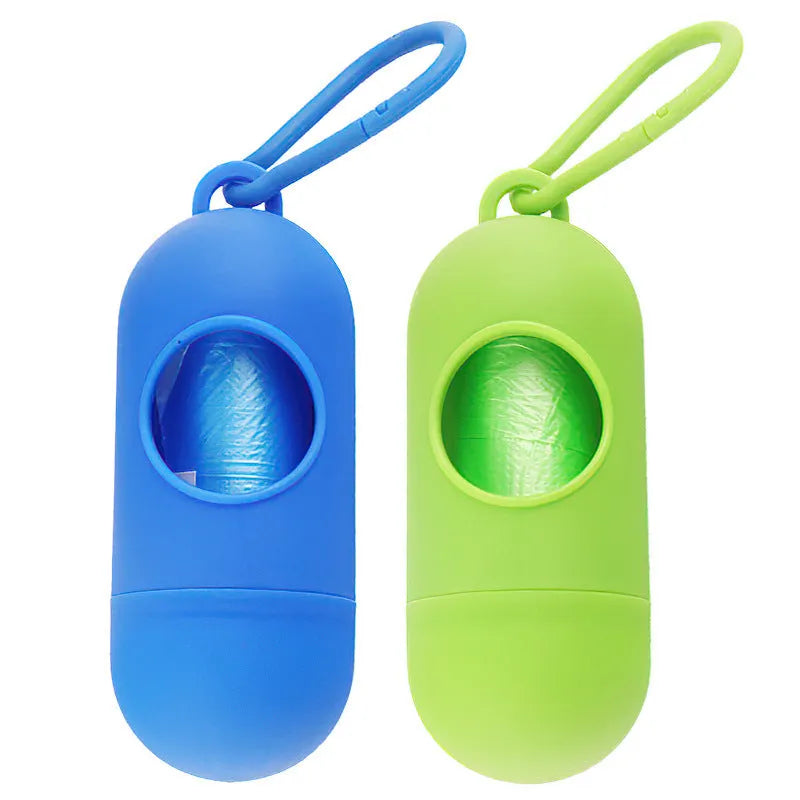 Compact black dog waste bag holder with a metal hook and Velcro strap, shown next to a roll of bags.