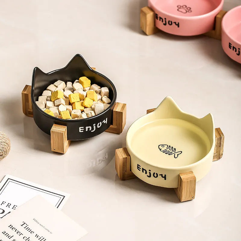 Porcelain cat bowl in a wooden anti-tip frame, showing cat's paw print design in pink.