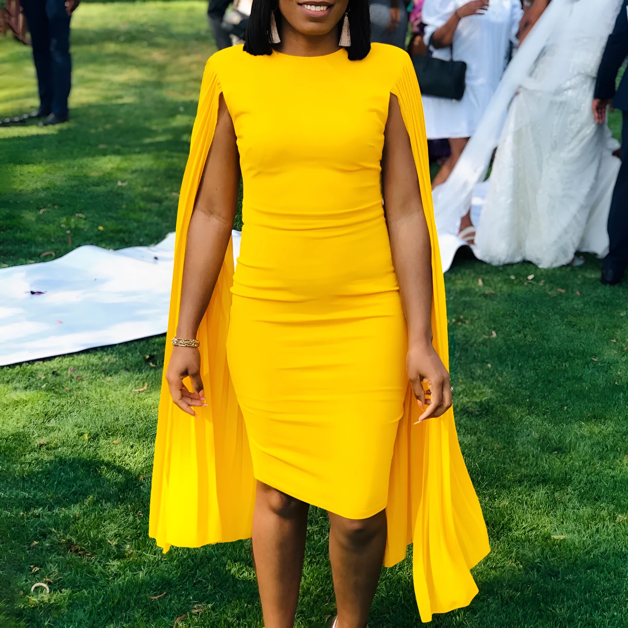 Yellow round neck long sleeve evening gown with high waist and pleated skirt on a model.